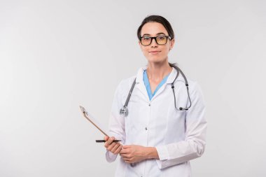 Whitecoat 'taki oldukça genç ve kendinden emin bir klinisyen kameranın önünde karantina altında dururken elinde bir dokümanla pano tutuyor.