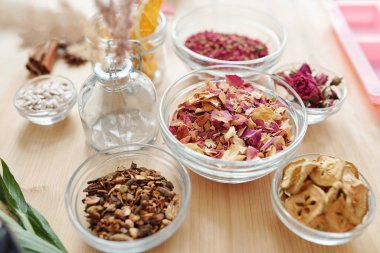 Kuru aromatik içerikli cam eşyalar ve ahşap masadaki baharatlar sabun yapımına hazır.