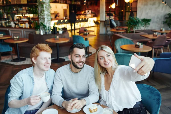 Tre Giovani Amici Felici Seduti Tavolo Caffè Accogliente Facendo Selfie — Foto Stock