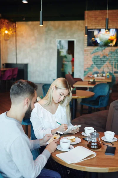 Samtida Kille Rulla Mobiltelefon Medan Blond Flicka Gör Anteckningar Eller — Stockfoto