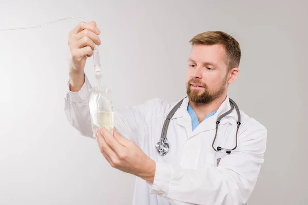 Young Bearded Clinician Stethoscope Holding Transparent Dropper Sack Liquid Medicine — Stock Photo, Image