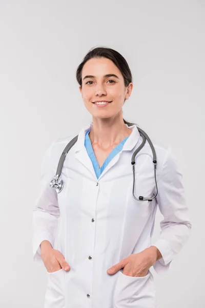 Joven Morena Sonriente Clínica Blanco Manteniendo Sus Manos Los Bolsillos — Foto de Stock