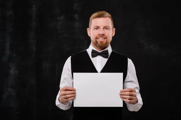 穿着黑色背心和领带 手握空白纸片 站在相机前 快乐优雅优雅的餐厅服务员 — 图库照片