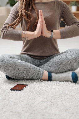Aktif kadın, yoga egzersizi sırasında bacak bacak bacak üstüne atarak yerde otururken ellerini göğüsten tutuyor.