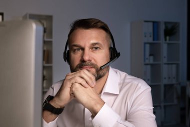 Ofiste bilgisayar ekranının önünde otururken sana bakan kulaklıklı ciddi bir telefon operatörü.