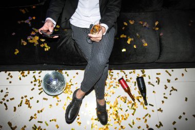 Akıllı telefonlu, flütlü, koltukta dinlenen ve mesajlaşan zarif bir genç adam.