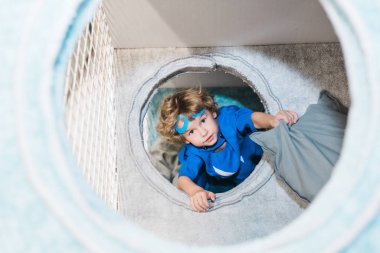 Sarışın, mavi kostümlü, süpermen kostümlü, çocuk odasında, dinlenme merkezinde oynayan küçük tatlı çocuk.