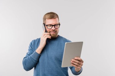 Gündelik kıyafetlerle meşgul bir ofis yöneticisi akıllı telefondaki müşterilere danışırken dokunmatik ekranlara bakıyor.