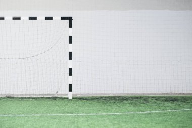 Çağdaş stadyumdaki beyaz duvara karşı boş bir futbol sahası, kapı ve ağ.