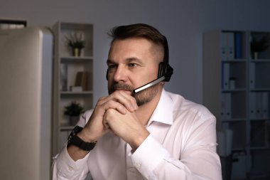 İş yerindeki müşterilere danışmanlık yaparken bilgisayar ekranına bakan ciddi bir telefon operatörü