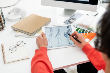 Mevsimlik koleksiyon için yeni modeller seçerken tablet ekranını işaret eden yaratıcı moda tasarımcısının elleri