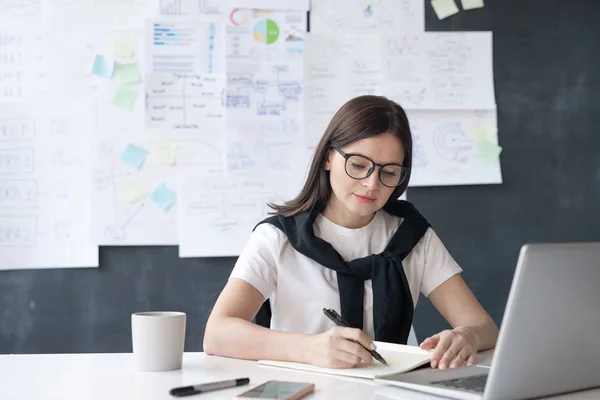 Serious Young Businesswoman Sitting Desk Front Laptop Making Notes Copybook — 스톡 사진