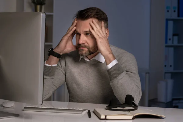 コンピュータの画面の前で働いている間に頭に触れる深刻で厄介なオフィスワーカー — ストック写真