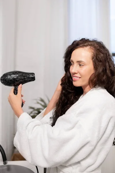 Mujer Sonriente Bastante Joven Con Secador Pelo Cuidando Cabello Ondulado —  Fotos de Stock