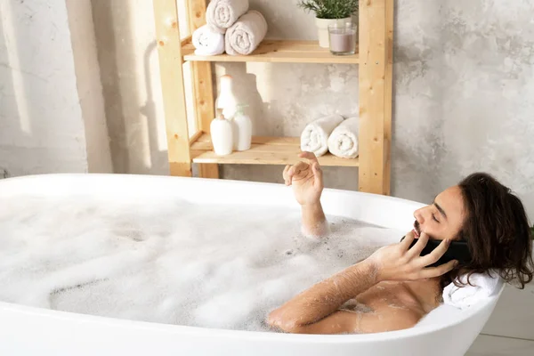 Joven Hombre Descansado Hablando Por Teléfono Inteligente Mientras Está Acostado — Foto de Stock