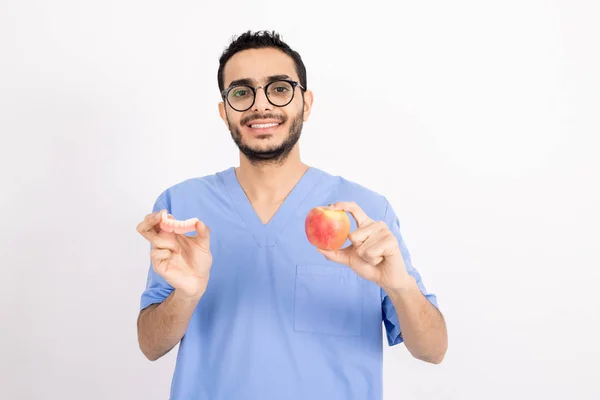 Smiling Young Dentist Blue Uniform Eyeglasses Showing You False Teeth — 스톡 사진