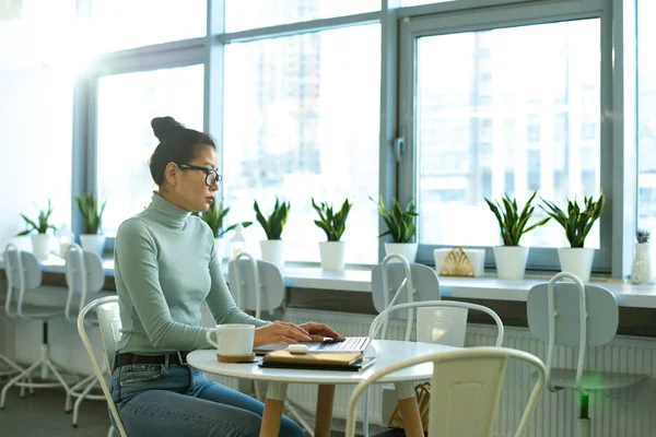 Allvarlig Kvinnlig Student Casualwear Sitter Vid Bordet Framför Laptop Samtidigt — Stockfoto