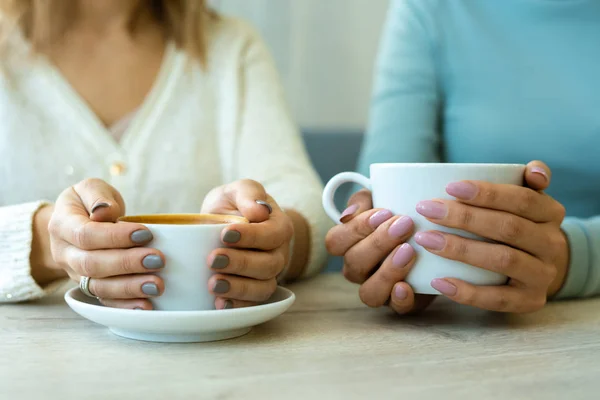 二人の若いフレンドリーな女性の手は カフェでテーブルに座ってコーヒーとカップを保持 — ストック写真