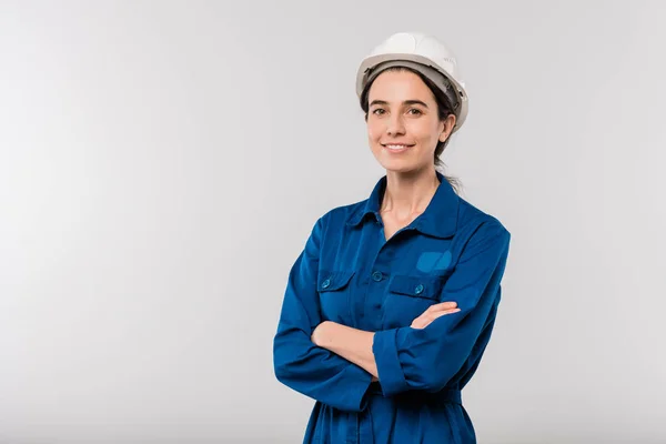 Glad Ung Korsbeväpnad Kvinnlig Ingenjör Blå Arbetskläder Och Hatt Står — Stockfoto