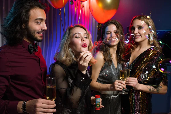 在夜总会的生日派对上 金发美女一边在朋友之间吹泡泡肥皂泡 — 图库照片