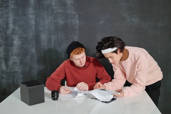 Twee Jonge Mannen Door Bureau Kijkend Door Papieren Met Toespraak — Stockfoto