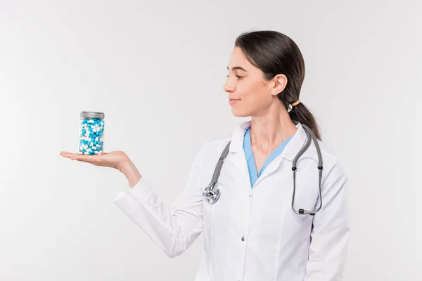 かなり若い女性臨床医や看護師ホワイトコート保持瓶に薬を手に隔離に立っている間 — ストック写真