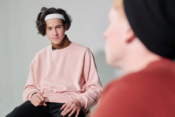 身穿粉红套头衫 头戴白色头巾 与维基百科互动的年轻而严肃的男人坐在他面前 — 图库照片