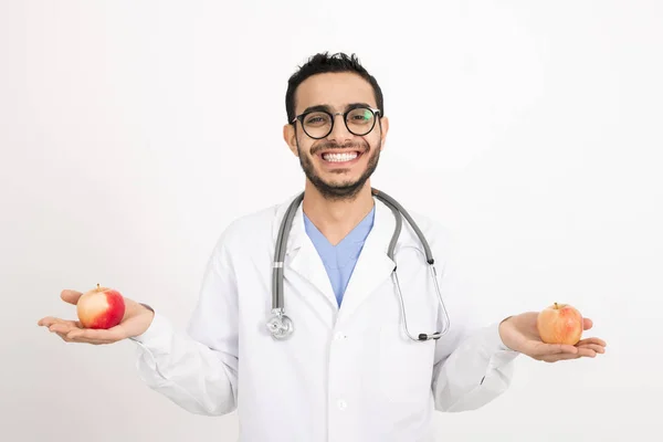 Alegre Dentista Con Sonrisa Dentada Sosteniendo Dos Manzanas Maduras Mientras — Foto de Stock