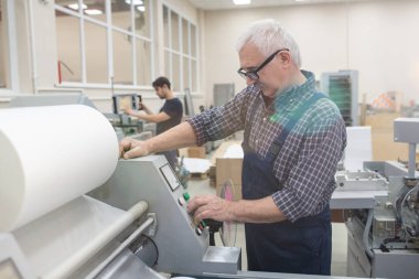 Yazdırma makinesi üzerinde çalışırken düğmelere basan gözlüklü ciddi kıdemli adam.