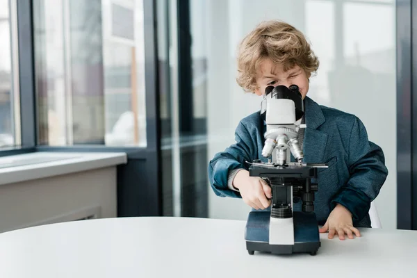 聪明可爱的男生或生物学家在教室或实验室的显微镜下 靠着桌子站着 — 图库照片