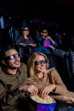 Büyük ekranın önünde oturup sinemanın tadını çıkarırken üç boyutlu gözlüklerle patlamış mısır yiyen mutlu randevular.