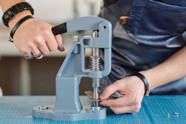 Önlüklü tanınmayan zanaatkârların yakın plan fotoğrafları. Deri kaplamalar için el baskısı kullanılıyor.