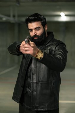 Acımasız sakallı suikastçı ya da siyah deri ceketli terörist ateş etmeden önce kurbana ya da rakibine silah doğrultuyor.