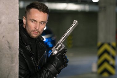 Siyah deri ceketli, eldivenli, tabancalı genç katil ya da ajan kurban ya da suçluyu vurmaya hazırlanıyor.