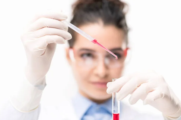 年轻临床医生或配戴手套的化学家在实验室用新疫苗将红色液体物质放入瓶中 — 图库照片