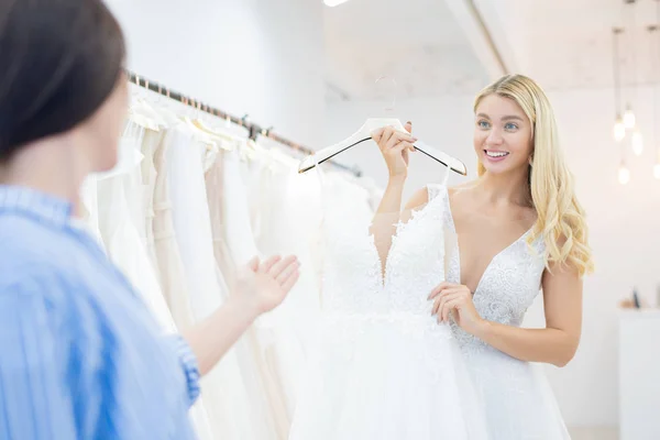 Волнует Красивая Невеста Вьющимися Волосами Показывая Свадебное Платье Другу Магазине — стоковое фото