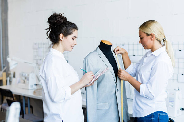 Блондинка в пиджаке, пока ее коллеги делают заметки в кетчпаде в ателье