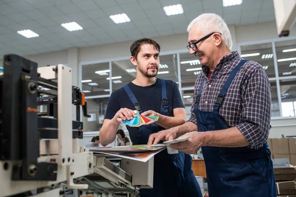 Smiling Senior Worker Uniform Watching Color Swatch While Discussing Colors — Stock Photo, Image