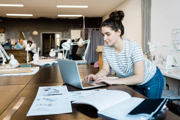 Sério Designer Roupas Jovens Usando Laptop Enquanto Examina Esboços Costura — Fotografia de Stock