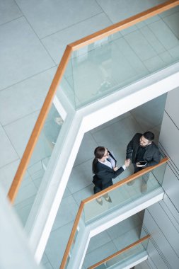 İş adamlarının balkonda durup müzakereden sonra el sıkışması.