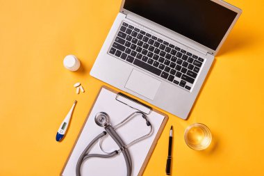 Horizontal from above flat lay shot of destop in modern doctor's office, yellow background