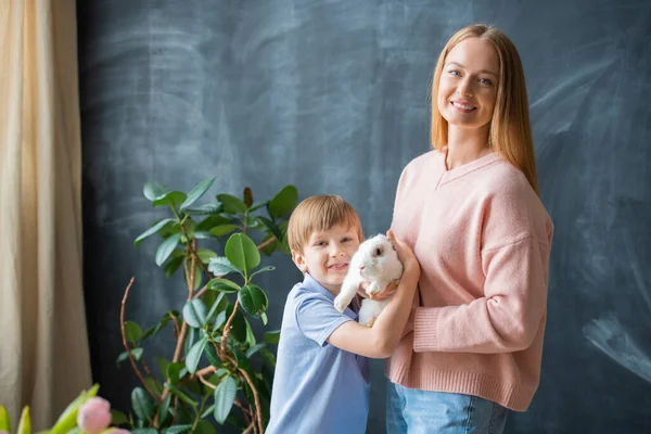 Retrato Joven Madre Positiva Hijo Posando Con Conejo Contra Pizarra —  Fotos de Stock