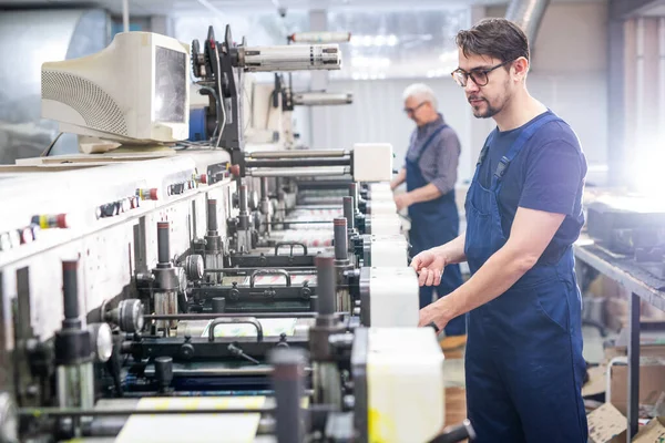 从事现代机器工作的蓝调印刷厂年轻而严肃的员工 — 图库照片