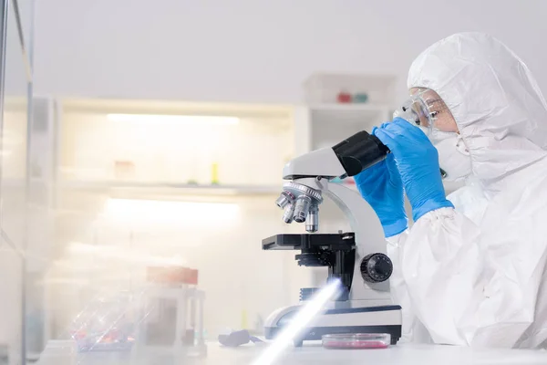 Focused Lab Technician Protective Suit Mask Using Microscope While Working — Stockfoto