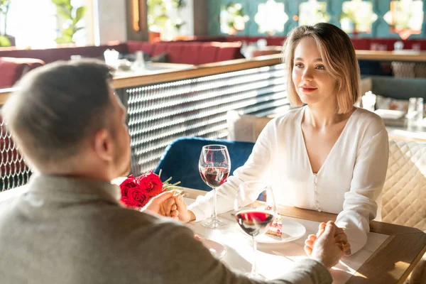 優しく手を取り合い お互いを見ているレストランのテーブルで 互いの前に座っている素敵な男と女 — ストック写真