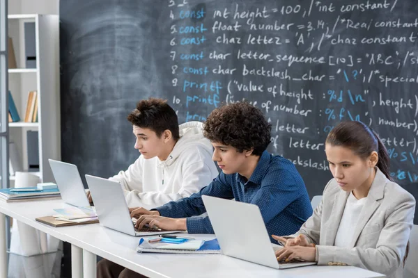 Wiersz Trzech Współczesnych Poważnych Studentów Współpracujących Przed Laptopami Siedząc Przy — Zdjęcie stockowe