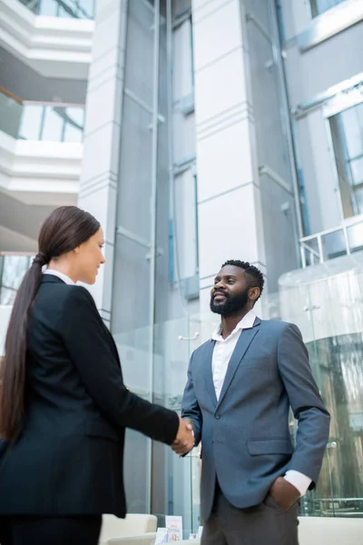 Confident Black businessman shaking hand of young business lady after signing contract