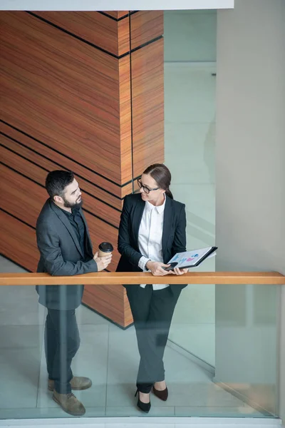 Above view of confident business experts in formalwear chatting about finances and budget in corridor