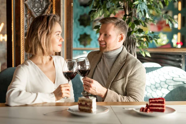 英俊的白人男人和美丽的女人坐在一起 餐桌边 酒杯叮当作响 红酒互相望着对方 — 图库照片