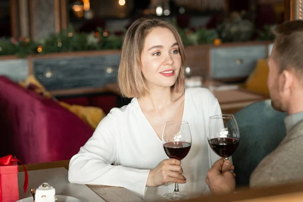 在现代餐馆里 一个漂亮的恋爱女人坐在男人面前 手里拿着酒杯和他聊天 这是一张横向的画像 — 图库照片
